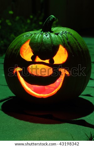 Halloween pumpkin carved into Jack O\' Lantern under green top light.