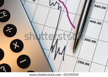 Financial chart, market\'s falling, calculator, pen, focus on chart at pen tip.