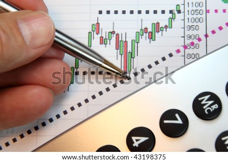 Financial chart, market\'s rising, calculator, pen, human hand, focus on chart at pen tip.