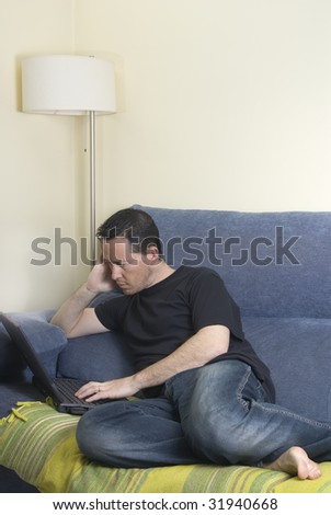 Teen on a sofa surfing the net with his laptop