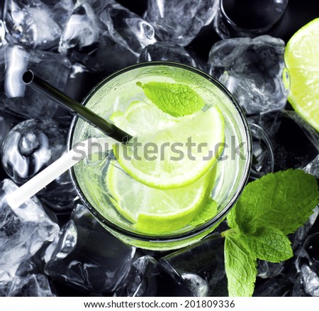 Mojito cocktail with fresh limes, mint and ice on black table
