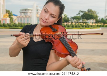 Woman playing the violin with beautiful buildings.