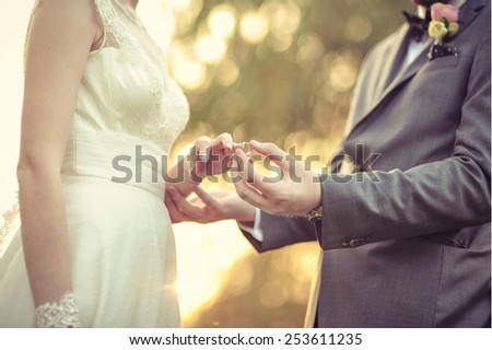 Groom putting the wedding ring on bride\'s finger