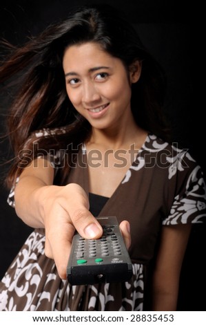 Young woman with TV remote control (focus on remote control).
