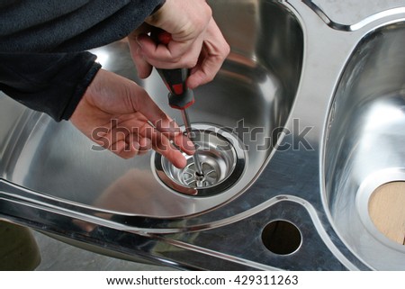 Plumber repairing the drain of a kitchen sink.