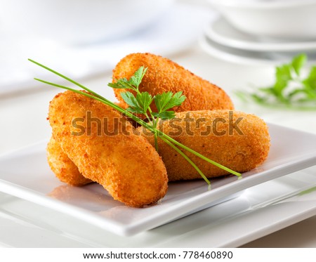 Homemade traditional Spanish croquettes or croquetas on a white plate with fork. Tapas food.