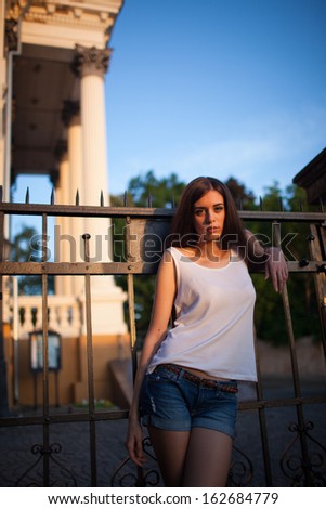 Image of a posing woman leaning on the fence.