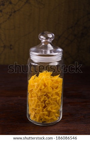 Raw pasta in glass jar on a dark wooden table