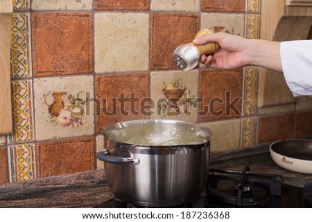 Man\'s hand adding salt into the hot water in the kitchen