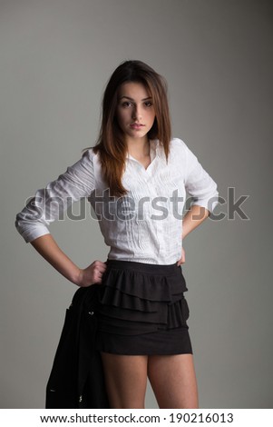Portrait of pretty fashion model in black and white clothes posing on studio background