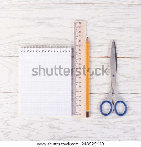 Notepad with pencil, ruler and scissors on wood table