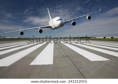 White airplane overflights low over the runway threshold