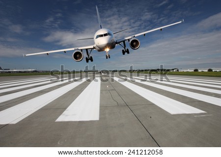 Landing aircraft low over the runway with stretched landing gear
