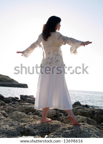 Beautiful young lady dancing on rocky sea shore