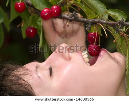 Beautiful young lady eats red cherry just from tree