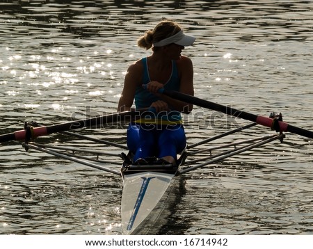 Sporty young lady rowing in boat on water dusk