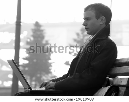 Young businessman working on laptop on bench outdoors