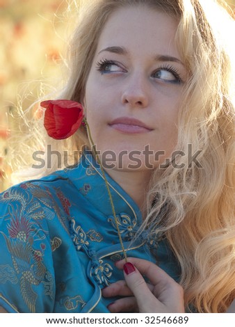 Beautiful blonde lady with poppy flower outdoors