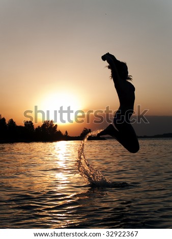 Lady in bikini jumping above water on sunset