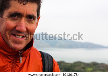 Close up of attractive middle aged man with brown hair looking at the camera smiling Outdoors with the bay in the background