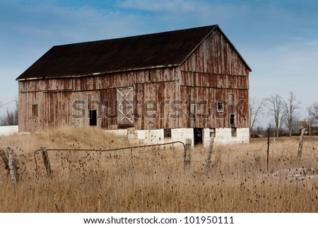 An old weathered bank barn with fields in the foreground