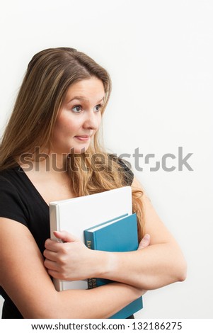 An attractive female college student with books waist up and angled to the camera