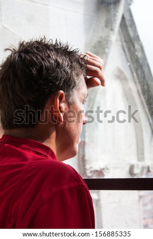 Taken at the Basilica in Quito Ecuador. A man muses while looking out a church window reflectively.  One of the church  peaks can be seen in the background outside.