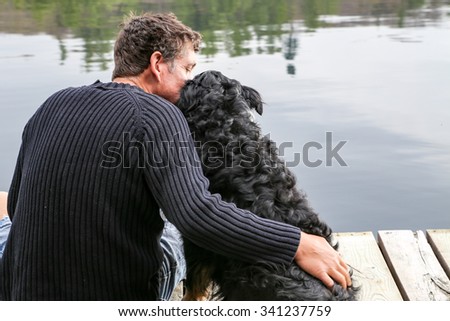 A man hugs his dog on the dock at the lake