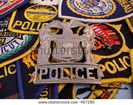 metal police emblem on a bed of police patches