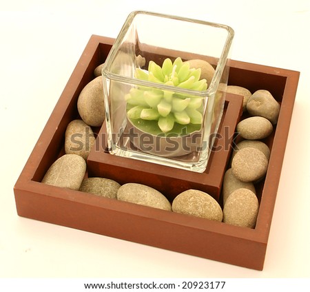 candle cactus-shaped in a glass placed in  square box with small stones