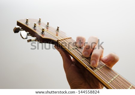 Neck of an acoustic guitar. A hand is holding the C major chord. White background.