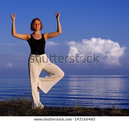Young woman doing yoga outside on the lake shore