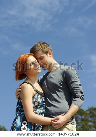Portrait of a young beautiful happy couple outside hugging and smiling