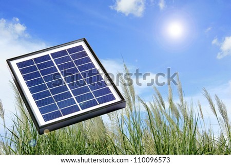 A solar panel on the green field under the sun.
