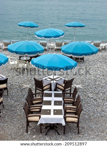 NICE, FRANCE - MAY 5: Beach and cafe with blue umbrellas near Promenade des Anglais on May 5, 2013 in Nice, France. There are many cafes and restaurants along the coast of the CÃ?Â?Ã?Â´te d\'Azur.