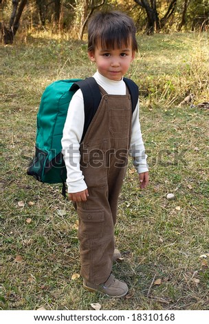 Little funny boy stands with backpack just come back from school