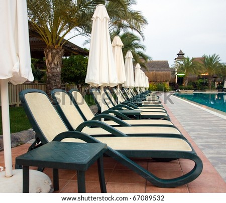 Chaise longue and umbrellas near the swimming pool.