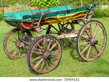 Ancient wooden cart standing on a green grass.