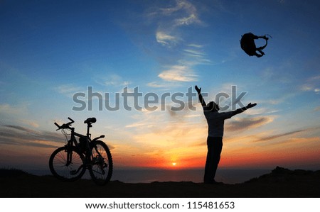 Tourist and bicycle at sunset by the sea