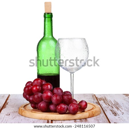 wine glass with red wine, bottle of wine and grapes on board isolated over white background