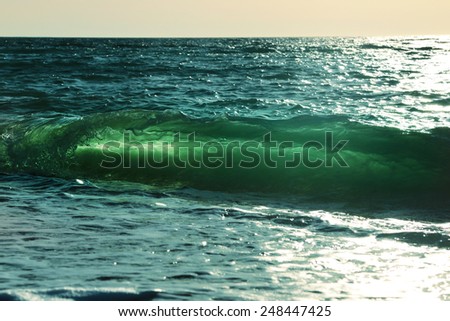 Ocean-view design postcard. Beautiful colorful breaking surfing ocean wave rushing at sunset time