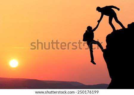 Teamwork couple hiking help each other trust assistance silhouette in mountains, sunset. Teamwork of two men hiker helping each other on top of mountain climbing team, beautiful sunset landscape.