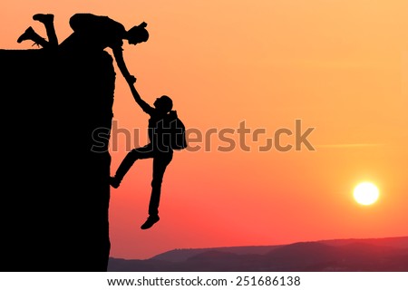 Teamwork couple hiking help each other trust assistance silhouette in mountains, sunset. Teamwork of man and woman hiker helping each other on top of mountain climbing team