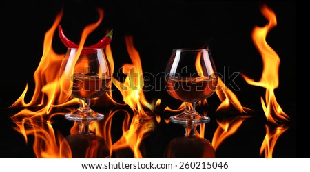 Hot chili pepper in a  cognac balloon with a fire on a black background