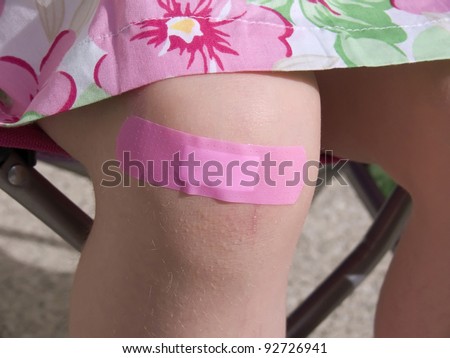 Little girl with an adhesive bandage on her sore knee.