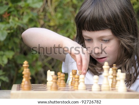 Little girl deep in thought as she contemplates her next move in a game of chess.