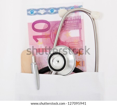 Doctors utensils plus 10 euro note in white coat.