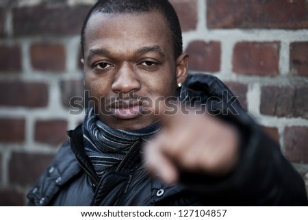 Attractive casual black guy outside points with finger