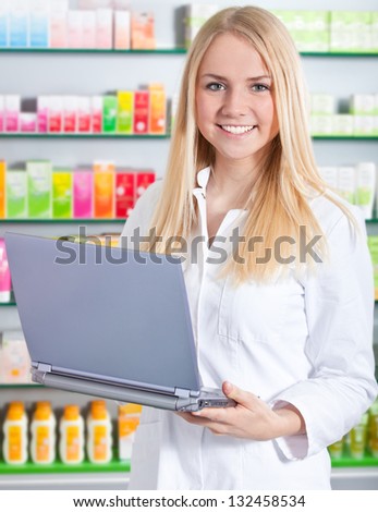 Attractive saleswoman in pharmacy using laptop.