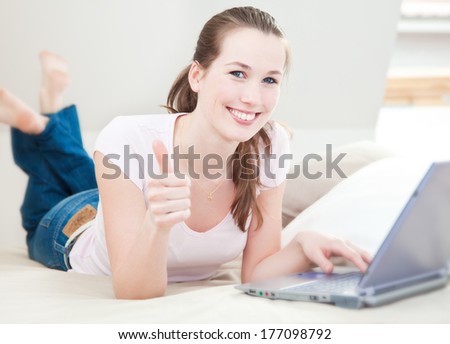 Attractive young woman using laptop showing thumbs up